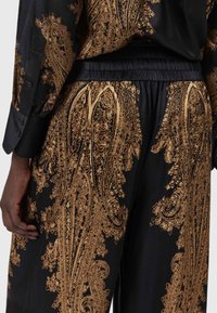 Must mustrakk mustri mustrifiga kuldse paisley mustriga, elastne vöökoht ja nööpidega mansettlooge särgil.