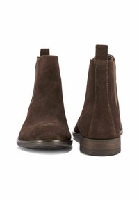 Brązowe zamszowe botki za kostkę z okrągłym noskiem i elastycznymi bocznymi panelami. Posiadają niski, warstwowy obcas oraz widoczne kontrastowe przeszycia.