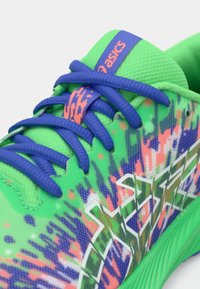 Πράσινο αθλητικό παπούτσι με υφασμάτινη επάνω επιφάνεια και ζωντανό, πολύχρωμο γραφικό σχέδιο, μπλε κορδόνια και επωνυμία στο μπροστινό τμήμα.
