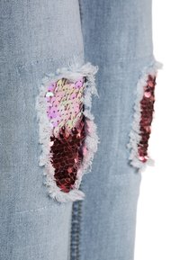 Jeans de mezclilla azul claro con parches desgastados que cuentan con brillantes lentejuelas rosas y rojas, bordes deshilachados y un diseño clásico de cinco bolsillos.