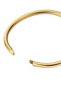 Pulsera de brazalete de metal en tono dorado, con un diseño abierto y redondeado, de textura suave y acabado pulido. Los extremos se estrechan ligeramente.