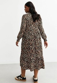 Luipaardprint midi-jurk met lange mouwen, een gerimpelde zoom en elastische manchetten. Gecombineerd met zwarte en beige sneakers. Zachte stoftextuur.
