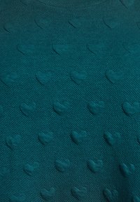 Tyrkysový svetr z texturované tkaniny s vzorem výrazných srdcí rovnoměrně rozmístěných po celé ploše, s žebrovaným výstřihem.