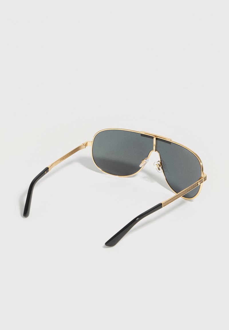 Gold-framed aviator sunglasses with dark lenses and black temple tips, laid flat on a white surface.