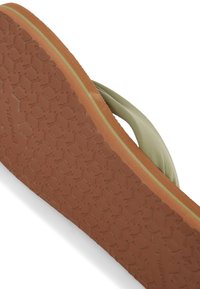 Grøn flip-flop med en tekstureret gummisål. Har en brun bund og honningkombination mønster for greb. Bløde stofstropper giver komfort.