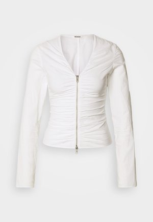 Bela oprijeta majica z dolgimi rokavi, z zadrgo spredaj in nabranim detajlom tkanine od ramen do pasu.