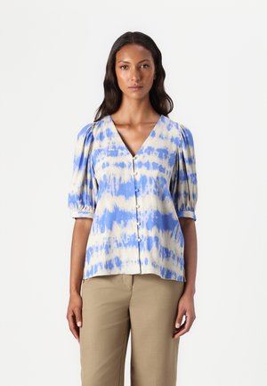 Lys beige skjorte med blå tie-dye-mønster. Har korte puffermer, V-hals og løs passform. Glatt tekstur.