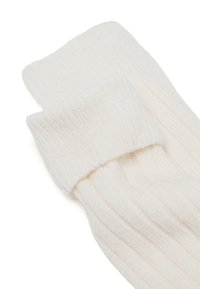Calcetines de lana de punto blando y blanco con puños doblados, mostrados apilados sobre un fondo blanco.