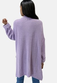 Lavenden gebreide cardigan met een losse pasvorm, verlaagde schouders en geribde manchetten. Getextureerde weefsel, lengte tot halverwege de dij en zijsplitten.