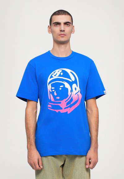 T-shirt en coton bleu présentant un grand graphique d'astronaute blanc et rose sur le devant. Manches courtes et col ras du cou, coupe décontractée.