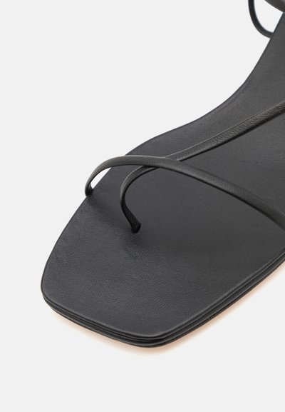 Mustat litteät sandaalit, jotka on valmistettu teksturoidusta synteettisestä materiaalista, joissa on ohuet hihnat ja neliön muotoinen kärki, korostaen minimalistista eleganssia.