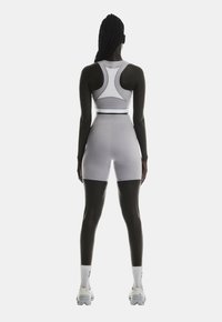 Un crop top de sport gris clair avec un dos nageur, associé à un short taille haute assorti, fabriqué en tissu extensible et lisse.