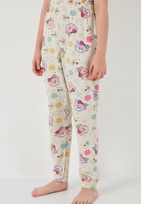 Pantalone od pidžame s krem podlogom i šarenim uzorcima crtanih medvjeda i cvjetova, elastična traka u struku i suženi donji dijelovi. Materijal: pamuk.