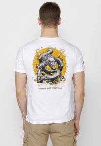 White cotton t-shirt featuring a detailed black and yellow dragon graphic on the back, surrounded by stylized waves and text.