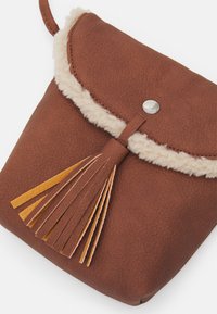 Bruine neplederen tas met een fluffy crèmekleurige rand, klepsluiting en een sierlijke tassel met gele en oranje strepen.