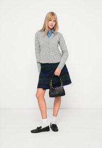 Siv kardigan z žebrički, modra srajca s ovratnikom, zeleni in mornarsko moder kiltski krilo, črna torbica s kovinskimi čepi, bele nogavice in črne loafer čevlje.