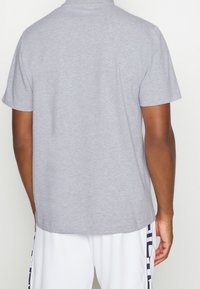 Szara koszulka z krótkim rękawem, wykonana z mieszanki bawełny, z okrągłym dekoltem, gładka w dotyku, z wykończonym brzegiem, bez widocznych wzorów czy ozdób.