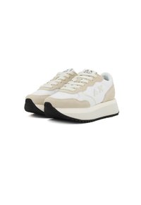Baskets beige et blanches en matériaux daim et mesh, avec une semelle en caoutchouc noir épais et des lacets, et un logo discret sur la languette.