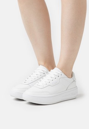 Sneaker bianche in pelle con punta rotonda, design con lacci e suola ammortizzata. Presentano dettagli minimi e un logo Fila sul lato.