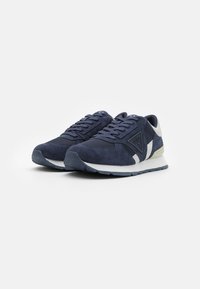 Sneakers blu navy con parte superiore in suede, dettagli in rete, accenti bianchi e suola in gomma con un motivo a rilievo.