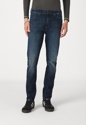 Jeans en denim bleu foncé avec une coupe droite, des détails de décoloration, un design traditionnel à cinq poches et une fermeture à bouton en métal.