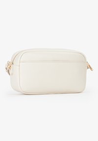 Borsa cosmetica in pelle color crema con forma rettangolare, chiusura superiore con zip e una superficie liscia. Presenta una piccola tasca frontale e accessori in oro.