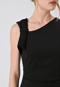 Schwarzes ärmelloses Kleid mit asymmetrischem Ausschnitt, ausgestattet mit einem Bindeband an der Schulter und einem glatten, dehnbaren Stoff.