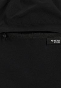 Schwarzer Stoff mit einem Reißverschluss und einem Etikett, auf dem "spitzbub STUDIOS" in Weiß steht. Die Textur wirkt glatt und langlebig.