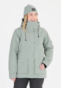 Ljusgrå vinterjacka med hög krage, justerbar huva och två framfickor. Ribbat mössa ger textur och kontrast.