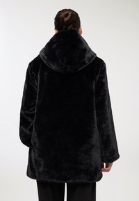 Czarny płaszcz z sztucznego futra z dużym kapturem, luźny krój i fakturowana powierzchnia. Gładkie rękawy i dół, co zapewnia miękki, pluszowy wygląd.