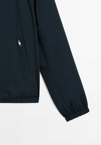 Navy blue windbreaker jacket, made of lightweight fabric, featuring an elastic hem and cuffs, and a zippered side pocket.