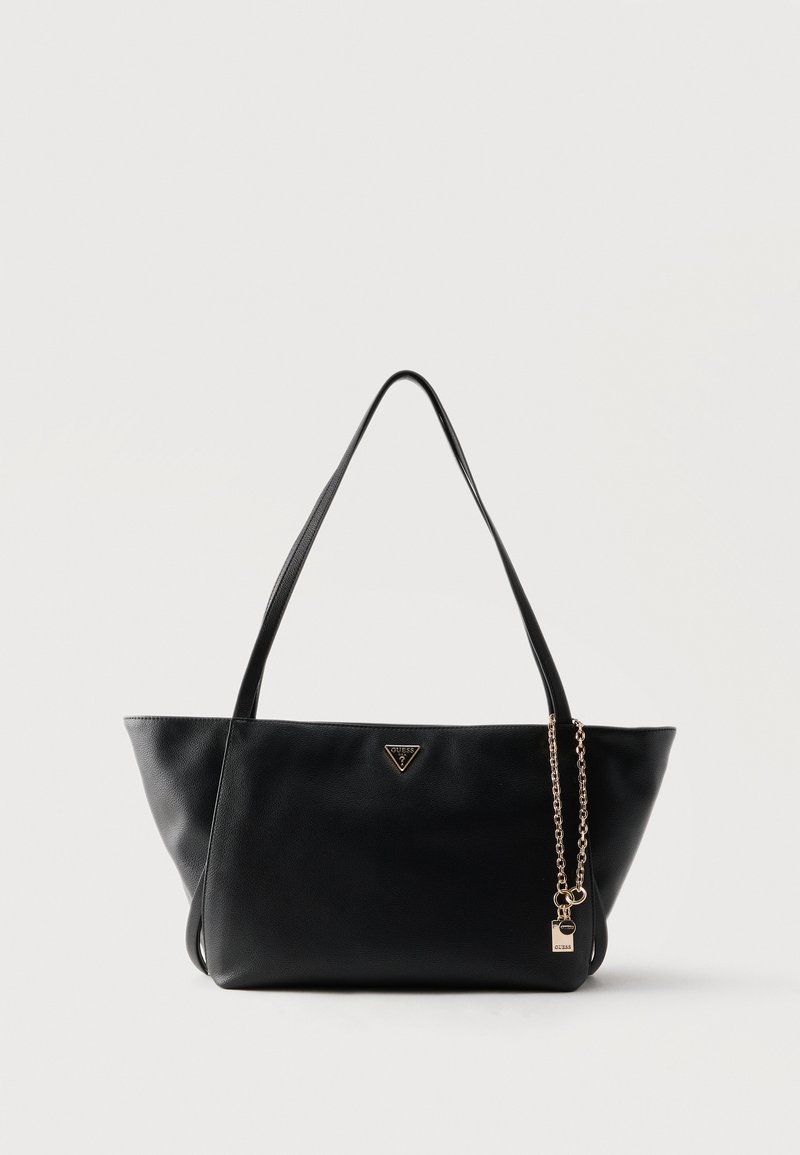 Sac cabas en cuir noir avec double poignée, logo triangulaire Guess et chaîne dorée avec breloque cadenas sur un fond uni.