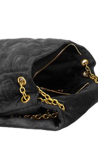 Zwarte suède handtas met gouden kettingaccenten en een ritssluiting, met een textuur aan de buitenkant en een gevoerde binnenkant.