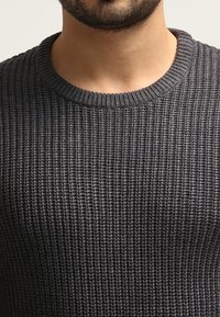 Donkergrijs gebreid sweater met een ribbelstructuur, ronde halslijn en een aansluitend design. Geschikt voor casual draag.