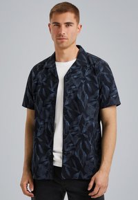 Camisa de manga corta con botones en azul marino oscuro con un patrón de hojas. Fabricada en tela texturizada, presenta un cuello tipo camp y un corte recto.
