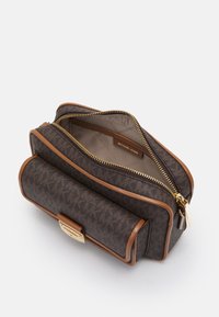 Hnědá kabelka se vzorem, se zlatými detaily, kontrastními světlými koženými akcenty, zipovým uzávěrem a strukturovaným designem. Interiér je z lehkého materiálu.