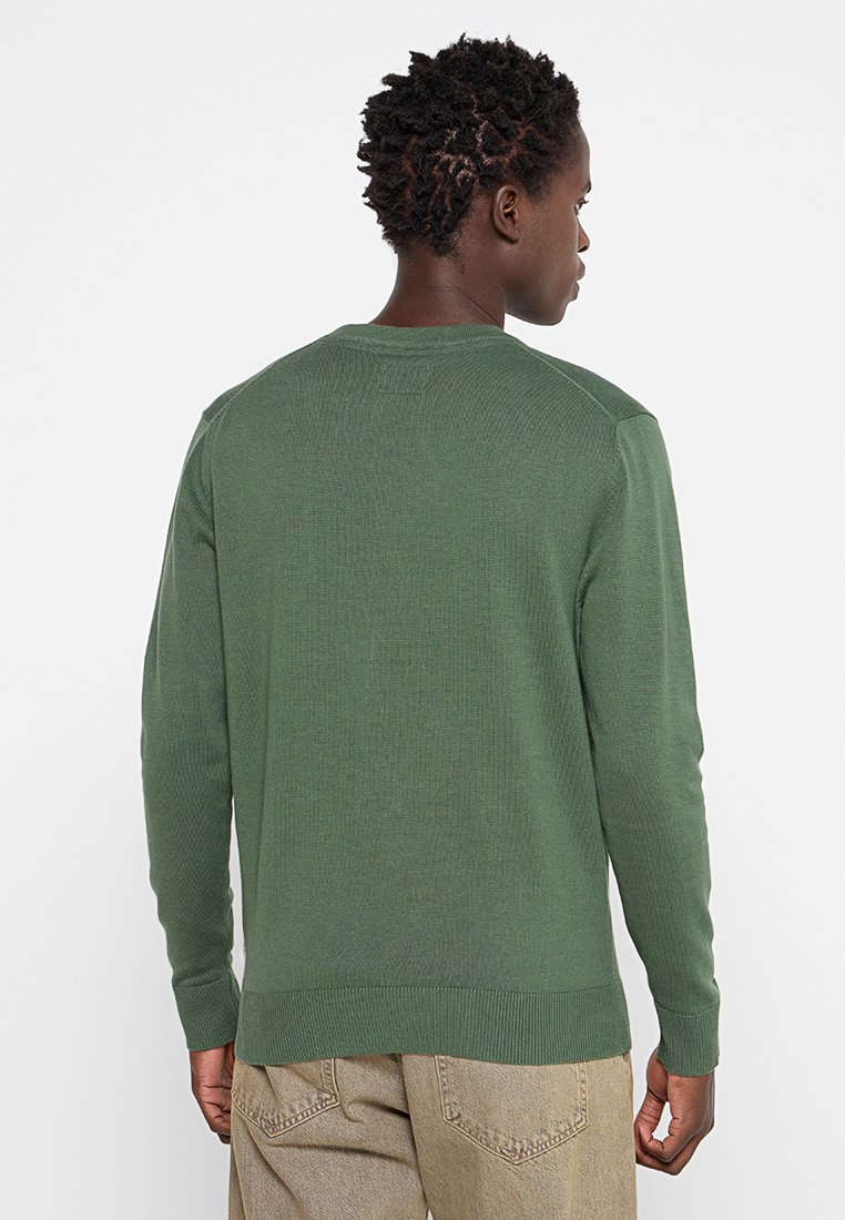 Pull en maille verte avec des manches longues, col et ourlet côtelés, texture légère et design simple. La vue de dos montre des coutures détaillées.