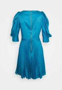 Robe bleu sarcelle à manches courtes avec un motif texturé, jupe plissée et une fermeture éclair dorée visible à l'arrière.