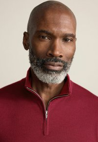 Pulover cu fermoar burgundy, cu guler înalt, fabricat dintr-un material tricotat moale, având un fermoar argintiu și detalii ribbate.