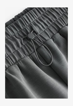 Közepe szürke sportnadrág, puha anyagból készült, ráncolt derékkal és állítható zsinórral, kerek díszítéssel.