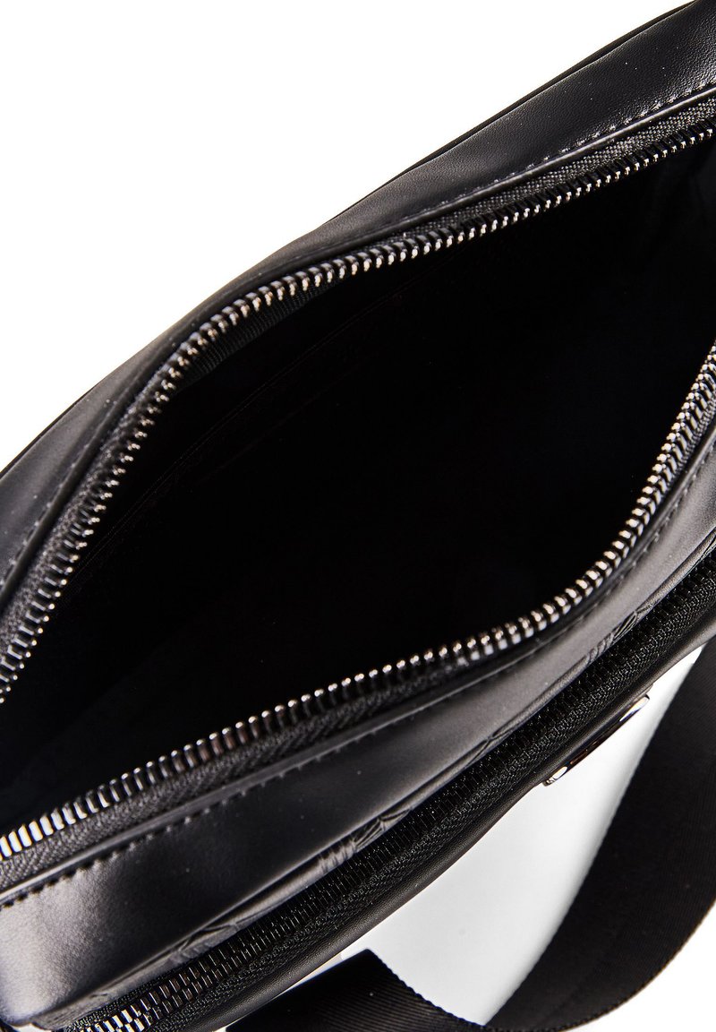 Black leather bag with silver zipper partially open, showing empty main compartment and attached black strap.