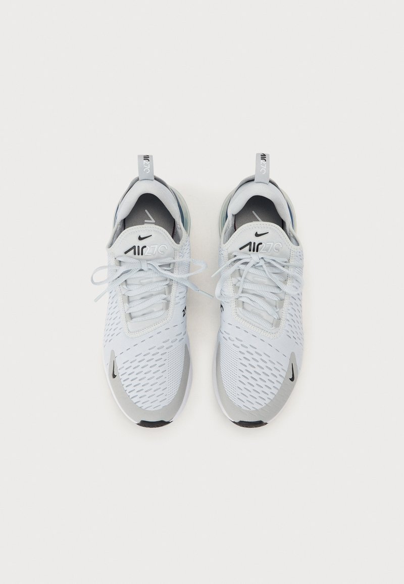 Zapatillas deportivas de malla blanca con acentos grises, puntera redonda, diseño con cordones y suela de goma negra; detalle del logo en el lado y la lengüeta.