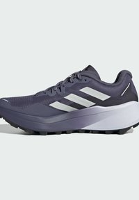Zapatilla de trail running en púrpura oscuro con acentos en blanco. Presenta una parte superior de malla, una suela gruesa y una suela exterior negra y rugosa para agarre.