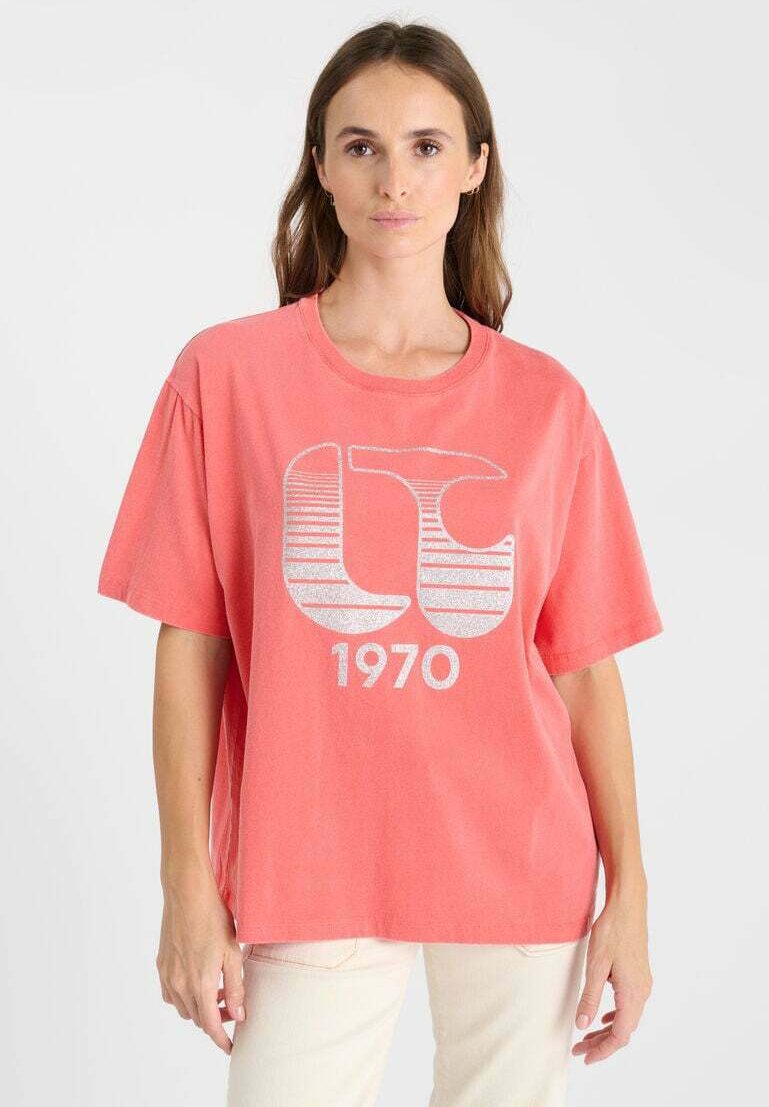 T-shirt surdimensionné couleur corail avec des manches courtes, arborant un imprimé graphique argenté "LC 1970" sur le devant, fabriqué en coton doux.