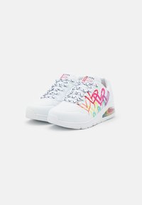 Weiße Sportschuhe mit bunten abstrakten Mustern in Pink, Gelb und Blau. Sie verfügen über schwarz-weiße Schnürsenkel und eine transparente Luftpolstersohle.