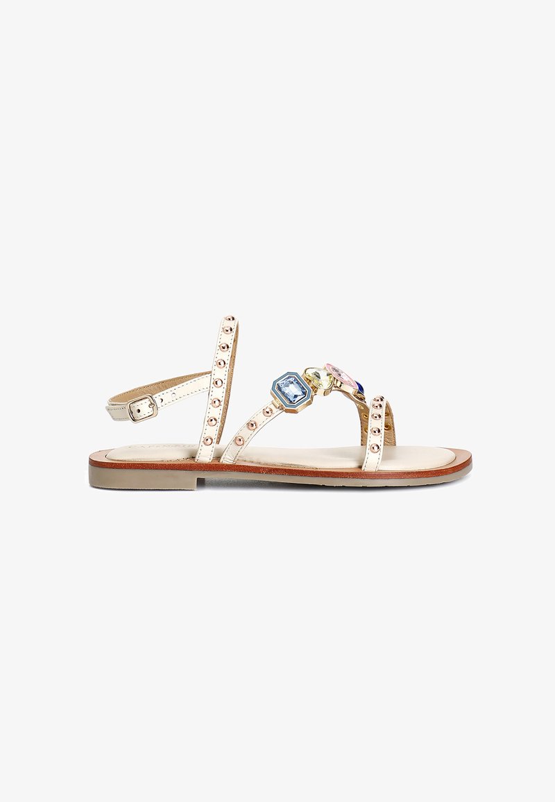 Sandali piatti con una finitura metallica beige, caratterizzati da tre gemme decorative, cinturini borchiati e una soletta imbottita.