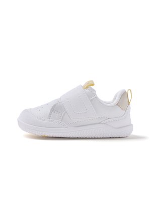Zapatilla deportiva blanca para niños con cierre de velcro, cuello acolchado y pestañas amarillas para tirar en la lengüeta y el talón, vista lateral sobre fondo blanco.