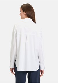 Witte blouse van gladde katoen, met lange mouwen, een rugplooien en een rechte snit met zijsplitten.