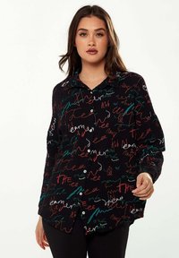 Button-up shirt in black fabric featuring colorful, abstract text patterns in red, white, and teal. Relaxed fit with a collar and long sleeves.