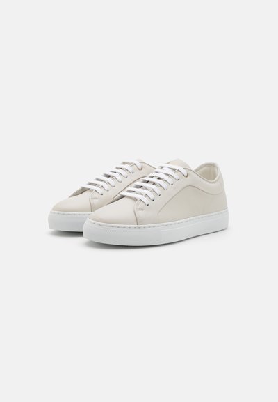 Beige leather sneakers with white laces, rounded toe, textured side panel, and a thick white rubber sole.